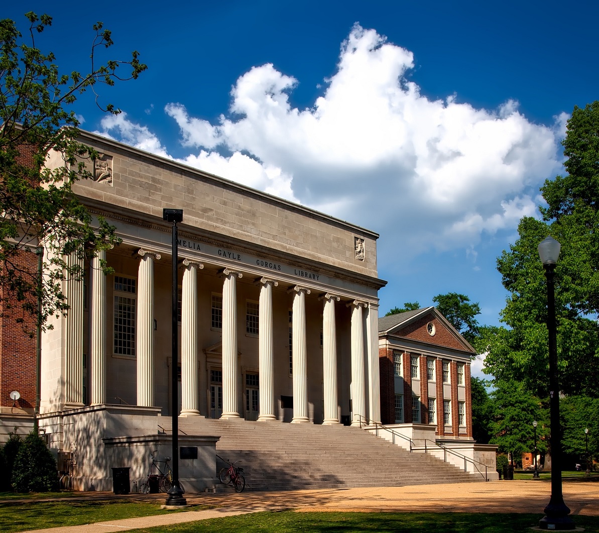 Campus Portal A grand building with tall white columns and a wide staircase, surrounded by green trees and a clear blue sky with white clouds, about Trinity Academic's focus on higher education institutions."